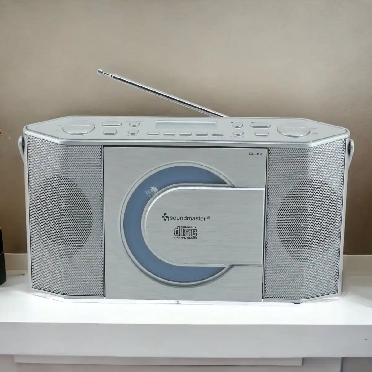 Silberner tragbarer CD-Player/Radiogerät mit eingebauten Lautsprechern und ausziehbarer Antenne.